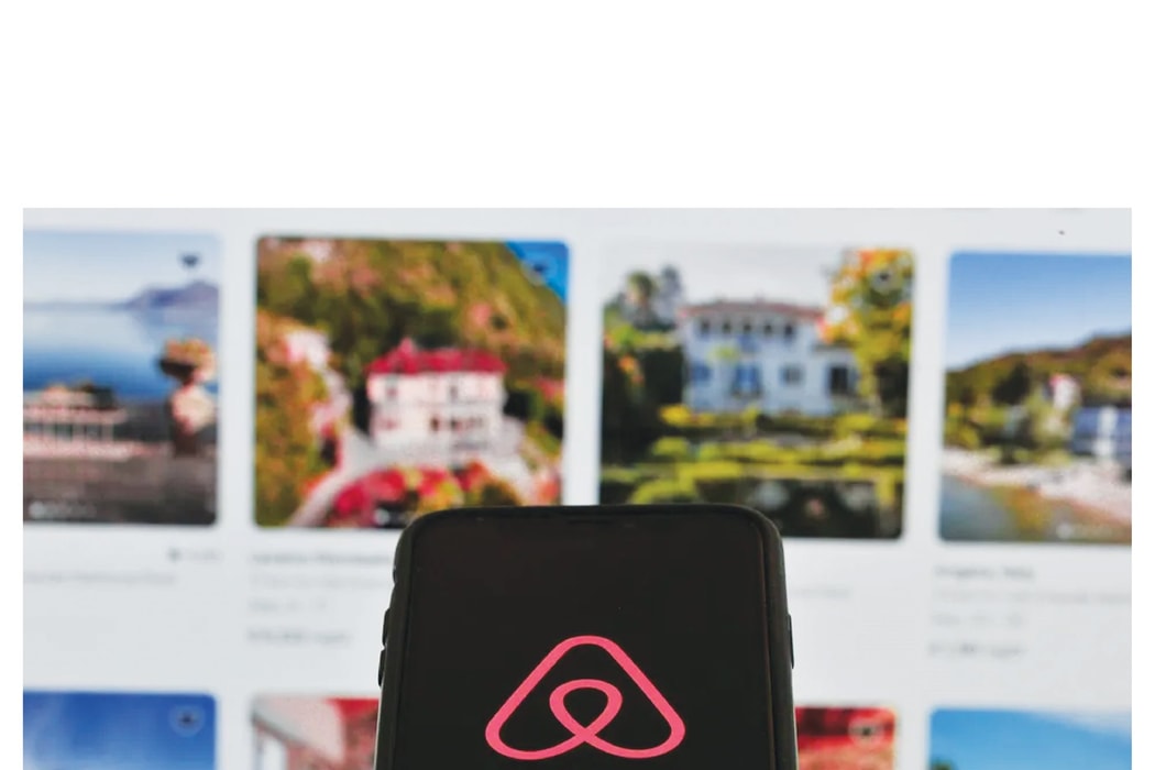 Logo Airbnb hiển thị trên điện thoại thông minh và trang chủ Airbnb trên máy tính được nhìn thấy tại L’Aquila, Ý, vào ngày 9 tháng 9 năm 2023. Một số thành phố đang áp đặt hạn chế đối với các chủ nhà Airbnb nhằm bảo vệ ngành khách sạn. Hình ảnh: Lorenzo D