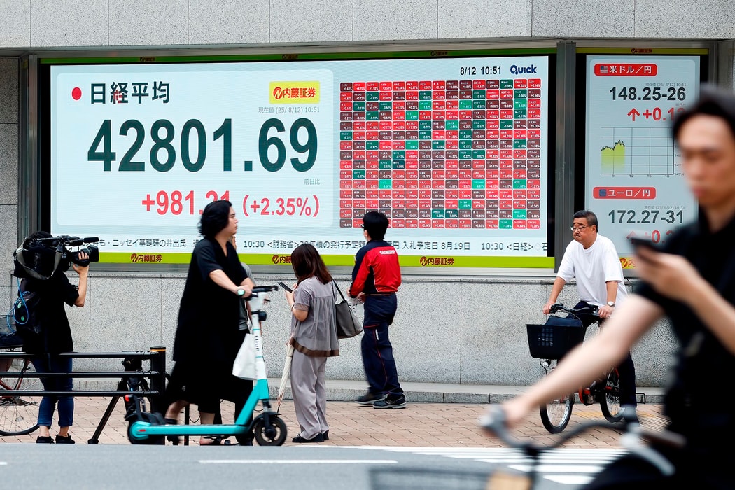 Màn hình hiển thị Chỉ số chứng khoán Nikkei 225 bên ngoài một công ty chứng khoán ở Tokyo, Nhật Bản, vào thứ Ba, ngày 12 tháng 8 năm 2025. Chỉ số Nikkei đạt mức cao nhất mọi thời đại vào thứ Ba khi sự lạc quan về thương mại toàn cầu thúc đẩy chỉ số blue-c